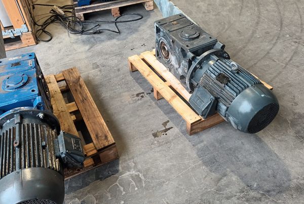 Deux motoréducteurs usagés posés sur des palettes dans l'atelier, en attente de révision