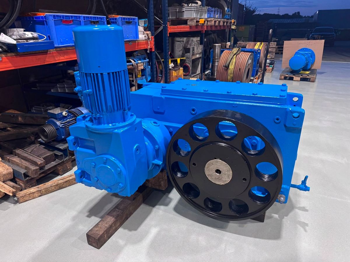 Réducteur bleu révisé avec vireur : moteur vertical et grande roue noire ajourée, en atelier