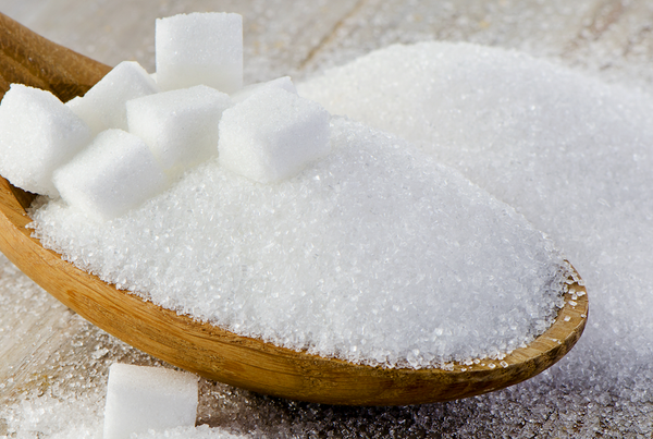 Sucre cristallisé dans une cuillère en bois avec des morceaux de sucre