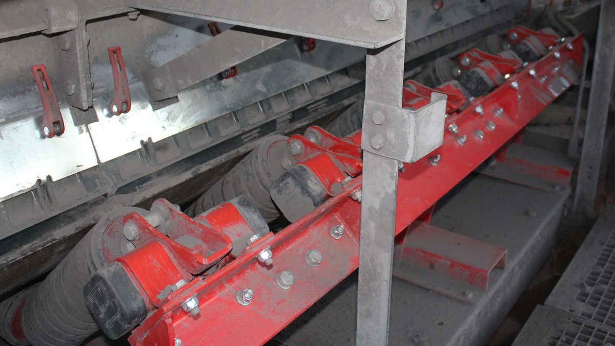 Schokdempende rollen met rubberringen op een rood frame onder de laadzone van een transporteur
