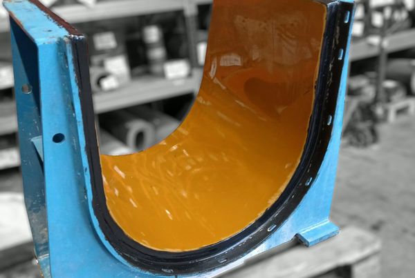 Pièce de chaudronnerie bleue en forme de U garnie à l'intérieur d'un revêtement jaune, devant des rayonnages d'atelier