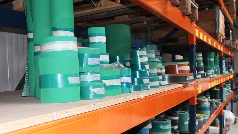 Rouleaux de courroies PVC et PU vertes empilés sur un rayonnage métallique