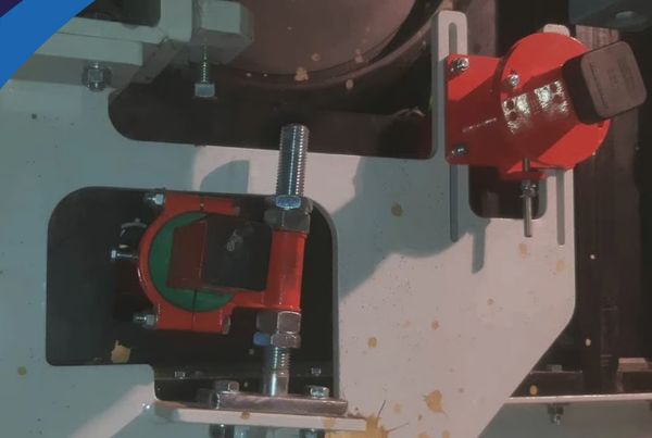 Deux racleurs Brelko rouges montés sur des supports adaptés d'un convoyeur à bande