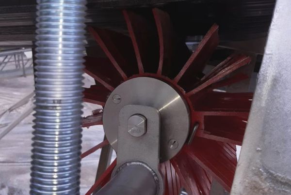 Brosse de raclage rotative à lamelles rouges, montée sur bras avec ressort sous la bande