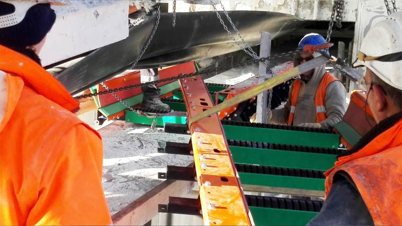 Trois techniciens placent une Optim'Auge sur site, sous une bande transporteuse