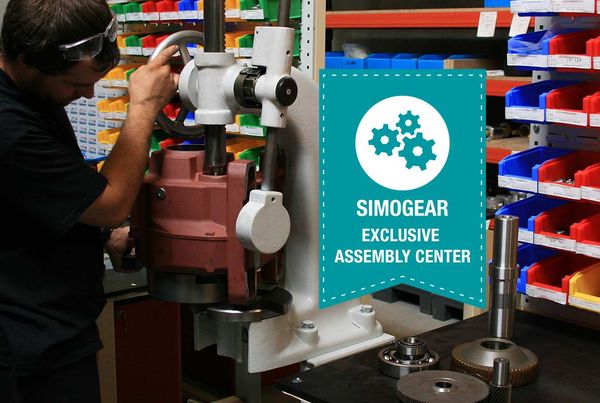 Technicien pressant un carter de réducteur rouge sous une presse d'atelier, badge « Simogear Exclusive Assembly Center »