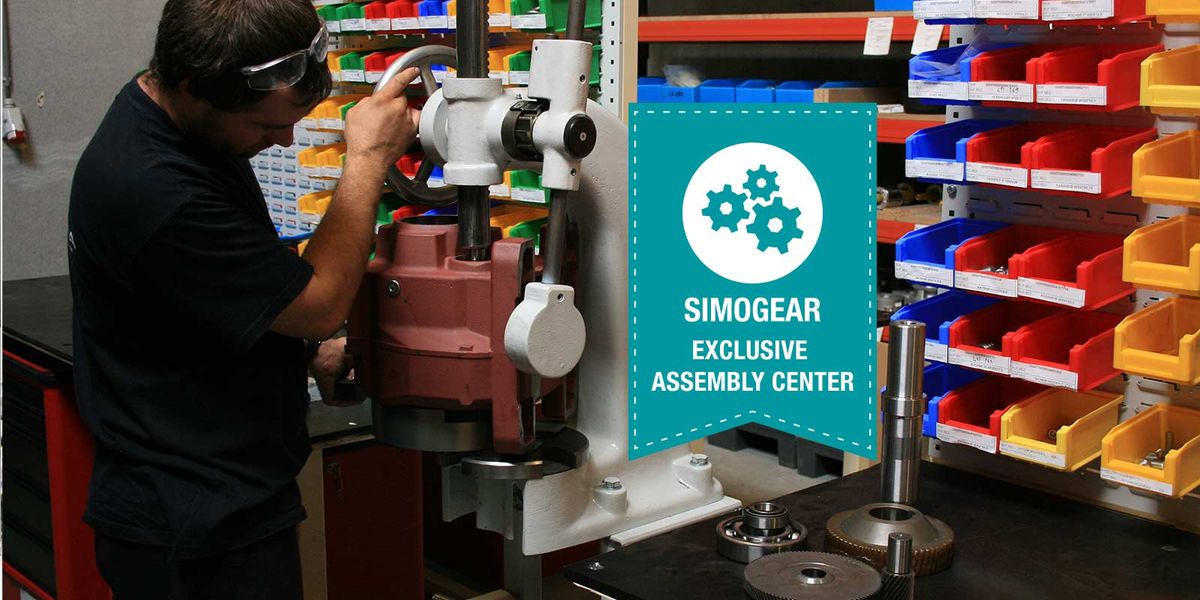 Technicien pressant un carter de réducteur rouge sous une presse d'atelier, badge « Simogear Exclusive Assembly Center »