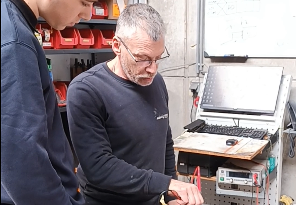 Apprenti et technicien ABM TECNA mesurant un petit moteur électrique sur un chariot d'atelier
