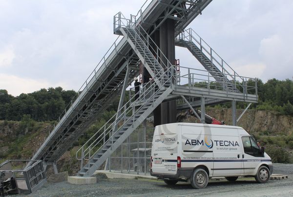 Convoyeur à bande incliné sur charpente treillis avec escalier et passerelle galvanisés, camionnette ABM TECNA devant