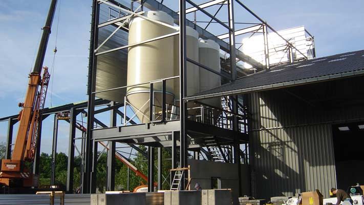 Montage d'une installation de silos blancs dans une structure métallique, grue à gauche