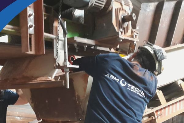 Technicien ABM TECNA intervenant sous un convoyeur à bande, au pied d'un motoréducteur