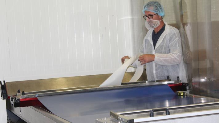 Technicus in voedingskledij plaatst een PVC PU-band op een verbindingspers in een productielijn