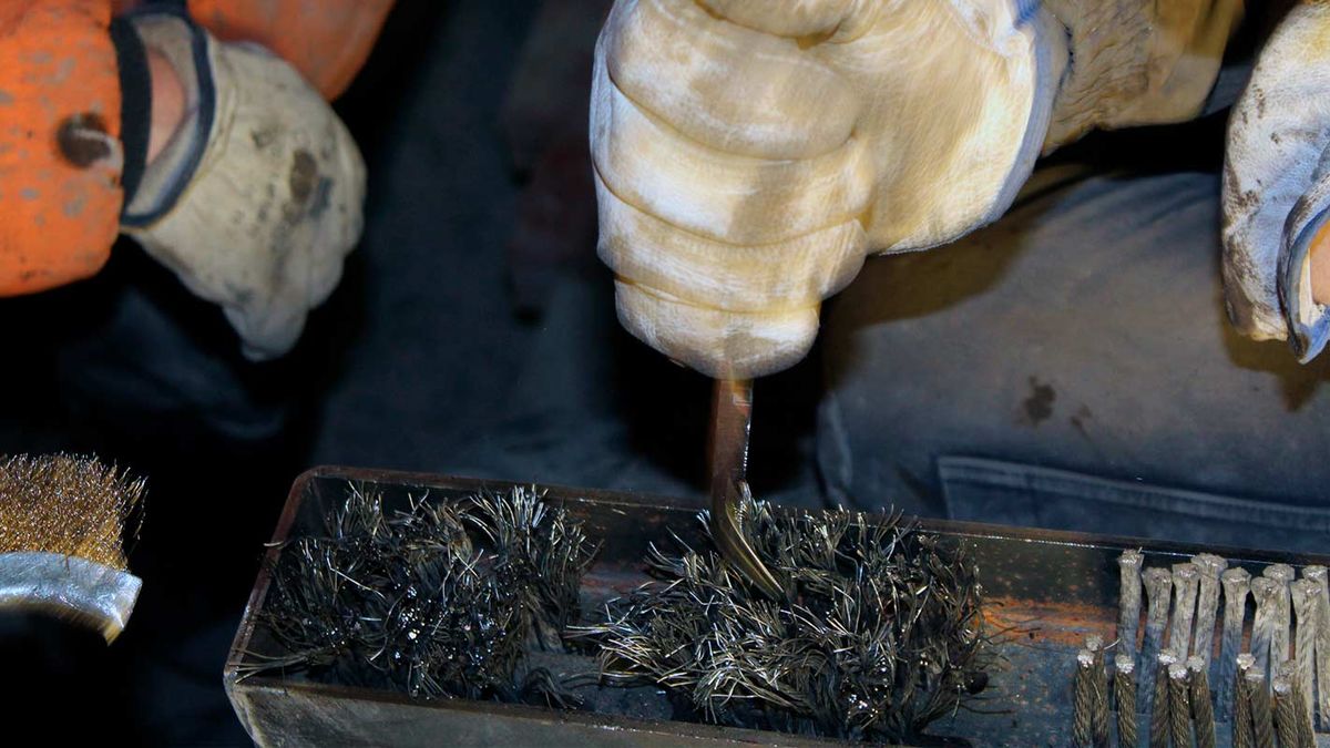 Close-up van een technicus met handschoen die een metalen verbinder in een bak met bevestigingen voor Beumer-band drukt