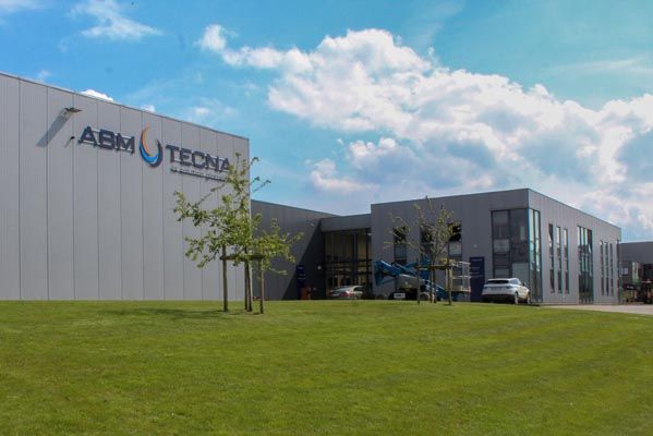 Siège d'ABM TECNA à Fleurus : bâtiment gris à bardage métallique avec enseigne, sur une pelouse