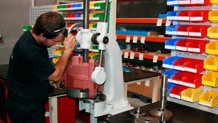 Technicus die een SIMOGEAR-motorreductor monteert op een werkplaatspers, opbergbakken achter hem