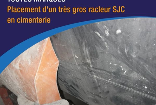 Service racleurs toutes marques : placement d'un très gros racleur SJC en cimenterie, main gantée tenant la lame